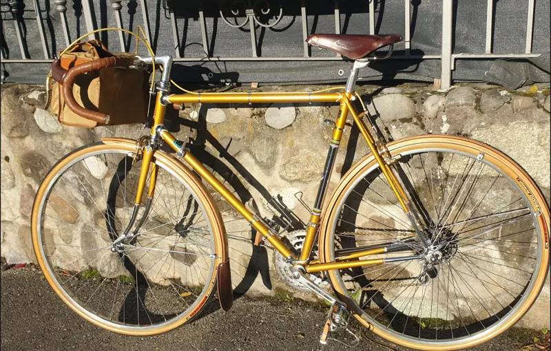 Randonneuse genevoise Cometti dorée avec garde-boue en bois, selle Brooks et sacoche de guidon